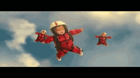 a baby in a red suit is flying through the air with two other babies