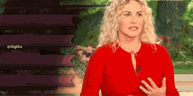 a woman in a red sweater is talking to a camera