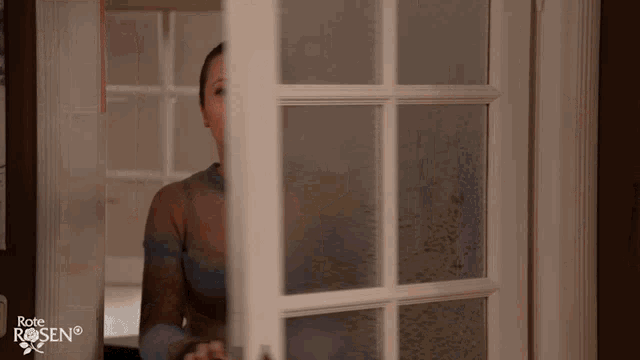 a woman stands in front of a door that has the word rose on it