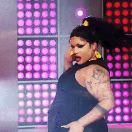 a drag queen is dancing on a stage in front of a crowd .