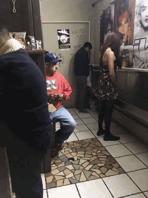 a man in a red marlboro sweatshirt sits on a stool