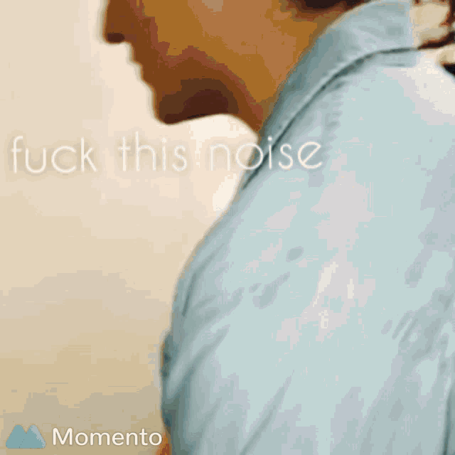 a man in a blue shirt stands in front of a wall with the words " fuck this noise " written on it