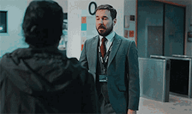 a man in a suit and tie talks to a woman in front of a sign that says 0