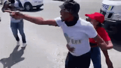 a man in a white shirt with the word eff on it is pointing at another man in a red hat