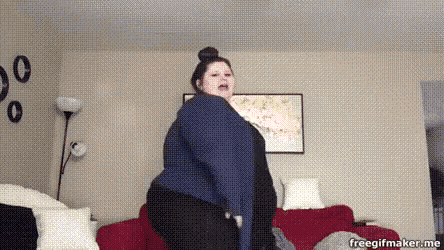 a woman is standing in a living room with a red couch .