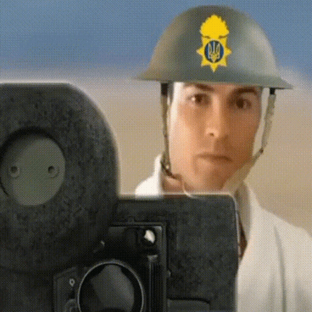 a man wearing a helmet with the ukrainian flag on it is taking a picture with a camera