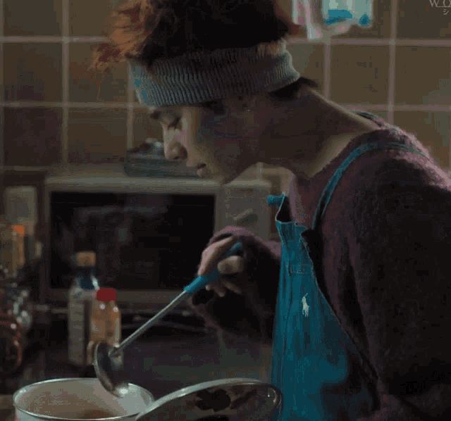 a man in a purple sweater is preparing food in a kitchen