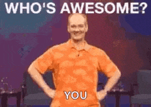 a man in an orange shirt is standing on a stage with his hands on his hips and says `` who 's awesome ? ''