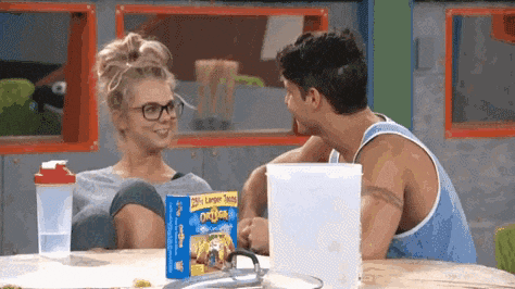 a man and a woman are sitting at a table with a box of oatmeal