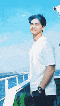 a young man in a white shirt is standing on a boat