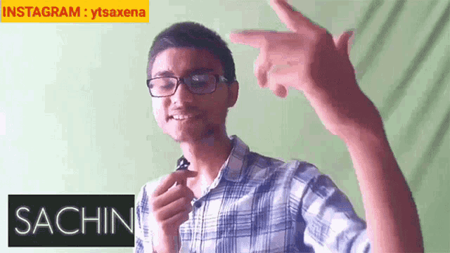 a man in a plaid shirt is pointing at the camera with the name sachin on the bottom right