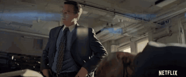 a man in a suit and tie is standing in a room with a netflix logo in the corner
