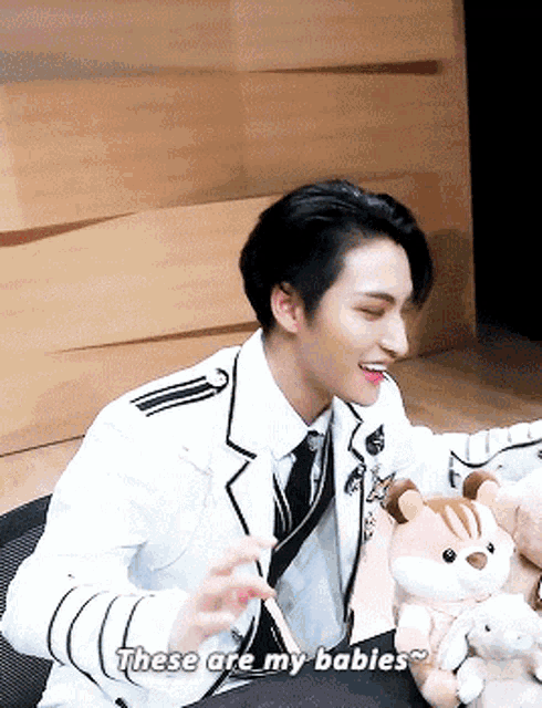 a man in a suit and tie is holding a stuffed animal and says these are my babies