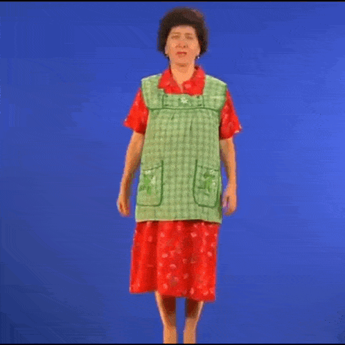 a woman in a green apron and red skirt is dancing on a blue screen .