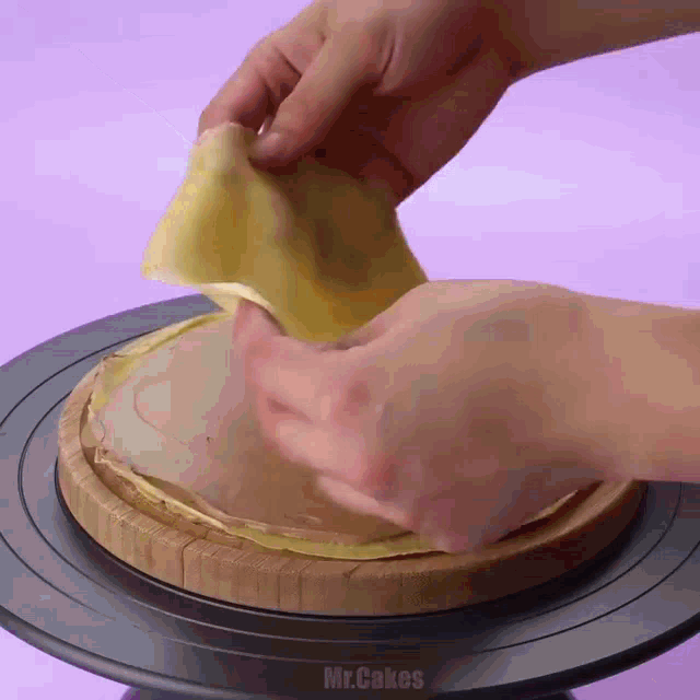 a person is holding a piece of food on a wooden cutting board that says mr.cakes