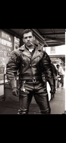 a man in a leather jacket is smoking a cigarette in front of a sign that says hr helper 's