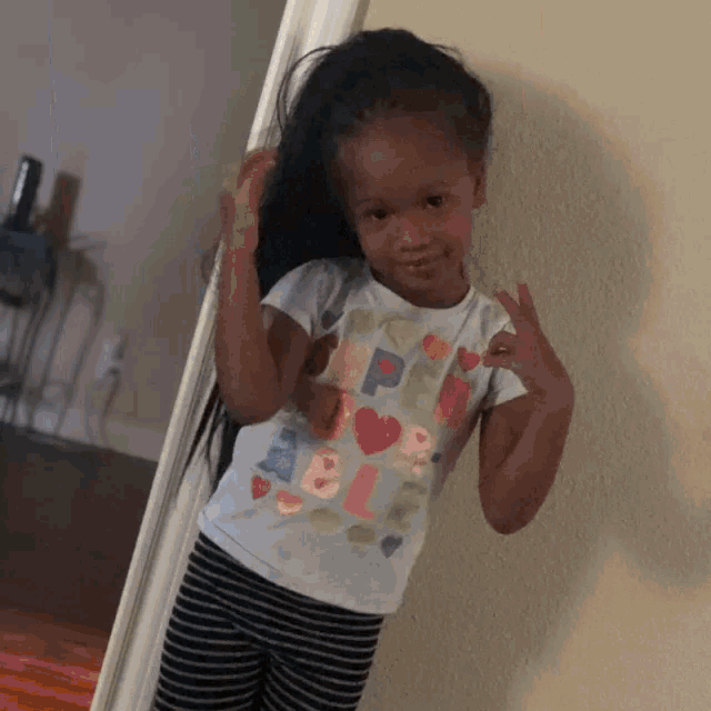 a little girl standing in front of a mirror wearing a shirt that says " happy valentines day "