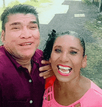 a man in a purple shirt and a woman in a pink shirt are posing for a picture