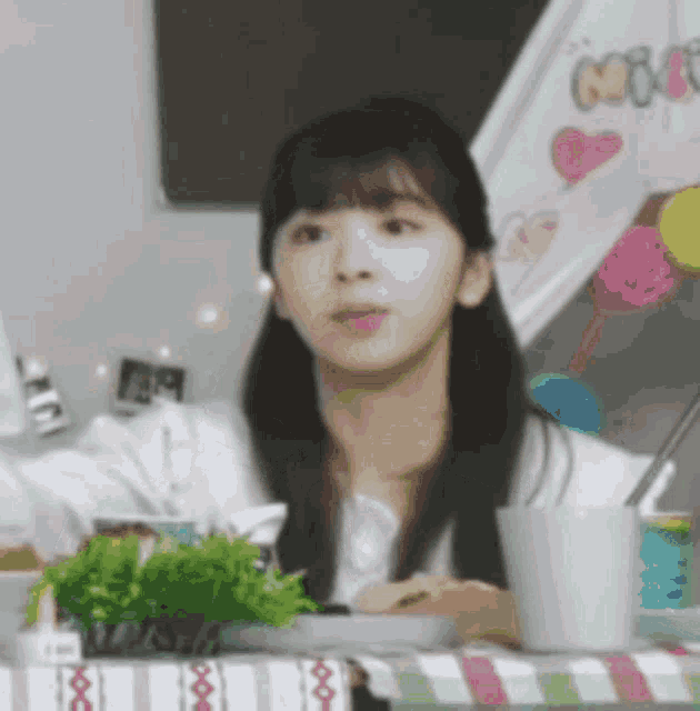 a woman is sitting at a table with a cup of coffee and a plant .
