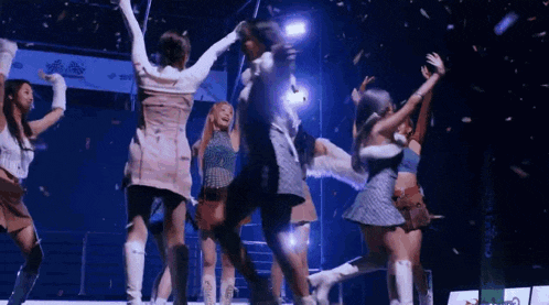 a group of women are dancing on a stage in front of a crowd .