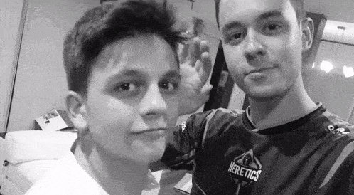 two boys are posing for a picture and one has a shirt that says heretics