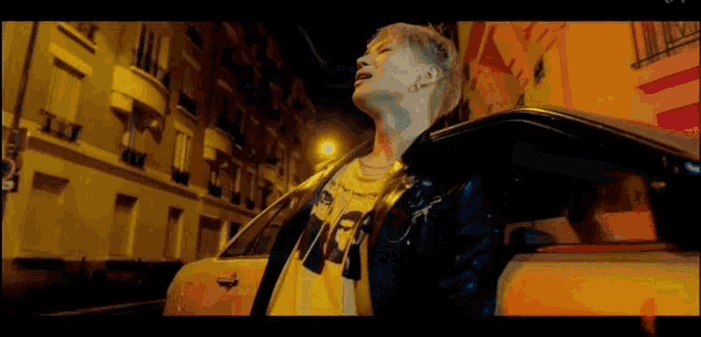 a man is standing next to a car on a street at night .