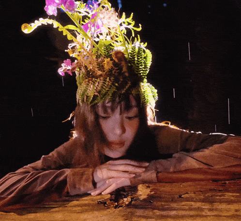 a woman wearing a hat with flowers and ferns on her head