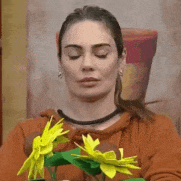 a woman with her eyes closed is holding a vase of flowers .
