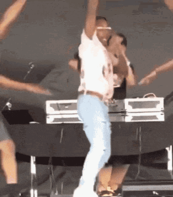 a man is dancing on a stage with his arms in the air while holding a microphone .
