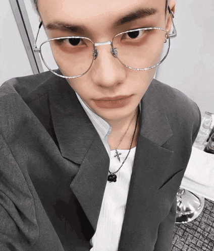 a man wearing glasses and a suit takes a selfie