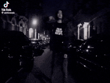 a black and white photo of a person standing next to a sign that says no parking