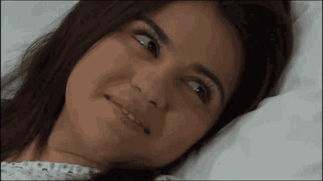 a woman is laying in a hospital bed and smiling at the camera