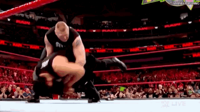 a wrestling match is taking place in a stadium with a crowd watching .