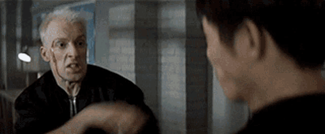 a man in a black jacket is talking to another man in a black jacket .