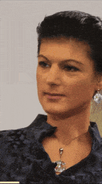 a woman wearing a necklace and earrings looks to the side
