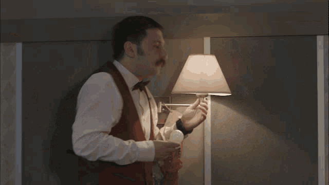 a man in a red vest is adjusting a light
