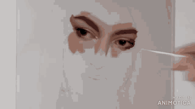 a close up of a person painting a woman 's eye with a brush