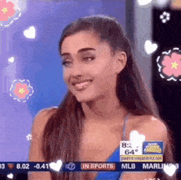 ariana grande is smiling and looking at the camera while sitting on a stage .