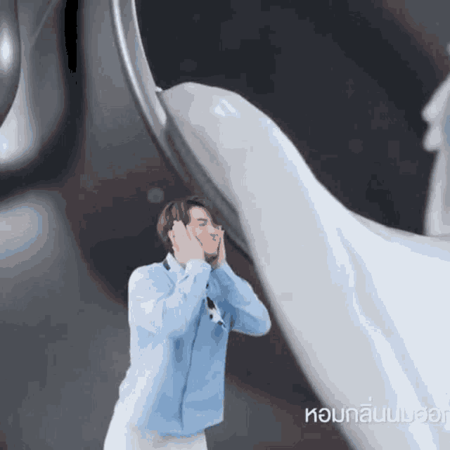 a man in a blue shirt is covering his ears in front of a white object