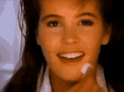 a close up of a woman 's face with a smile on her face and a toothbrush in her hand .