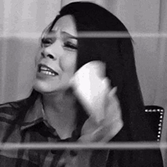 a woman with long hair is sitting in a chair talking on a cell phone .
