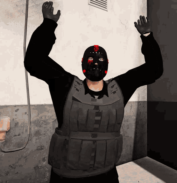a man wearing a black mask and a black vest has his arms up in the air
