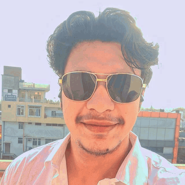 a man wearing sunglasses stands in front of a building that says ' shree ram ' on the front