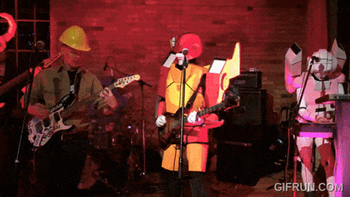 a group of people in hard hats are playing guitars and singing in front of a microphone with gifrun.com at the bottom