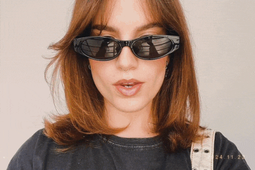 a woman wearing sunglasses and a black shirt has the date 24.11.22