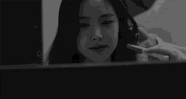a woman is smiling in a black and white photo while looking at a computer monitor .