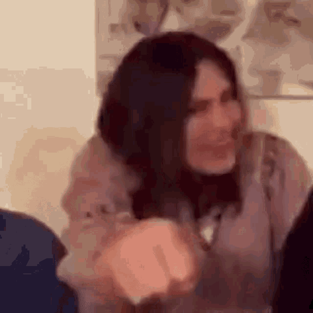 a woman is sitting at a table with a group of people and laughing .