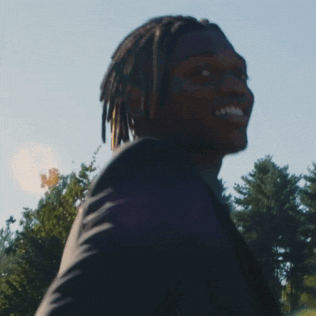 a man with dreadlocks is smiling while holding a cell phone