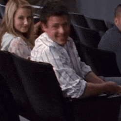 a man and a woman are sitting in a row of black chairs