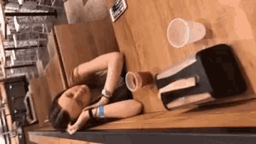 a woman is sleeping at a table with a napkin holder and a cup .